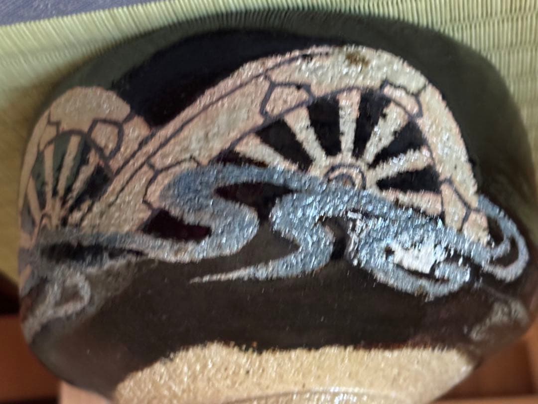黒楽　黒地に銀色や白で車輪模様と流水模様が描かれている