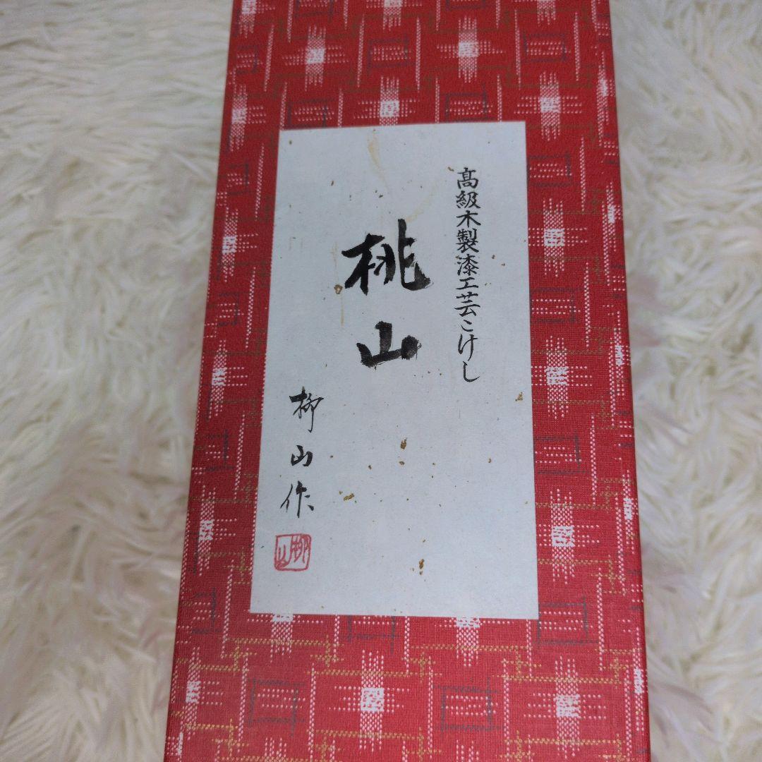 桃山 柳山作のこけしです。箱付き 落ち着いた木の風合いに、赤色の花模様