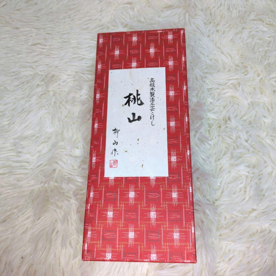 桃山 柳山作のこけしです。箱付き 落ち着いた木の風合いに、赤色の花模様